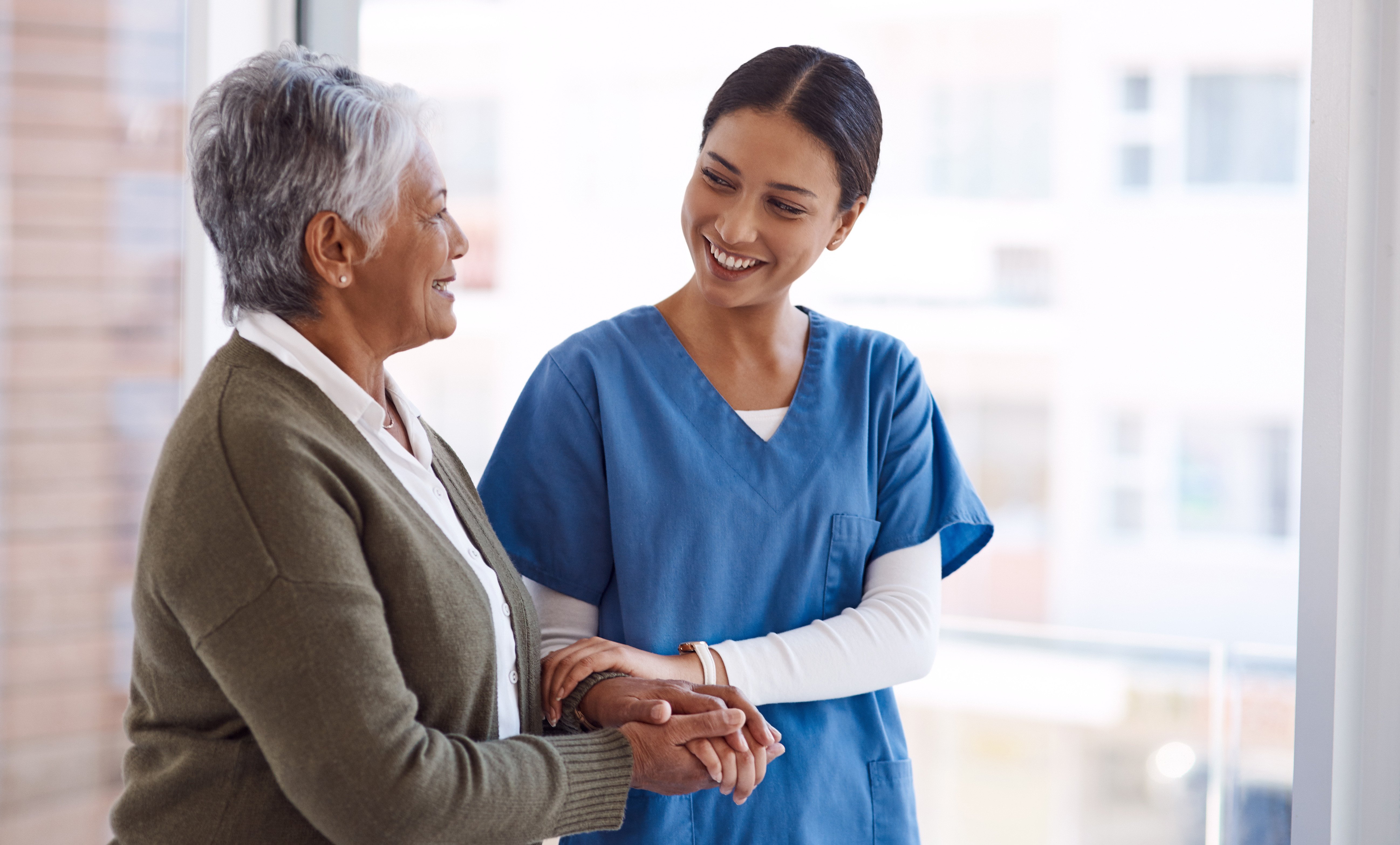 Professional female nurse with elderly person smiling together for healthcare at nursing home.